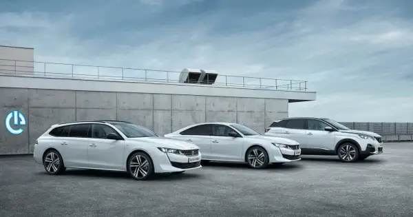 Trzy białe samochody Peugeot 508: kombi, sedan i SUV, stoją przed betonowym budynkiem.