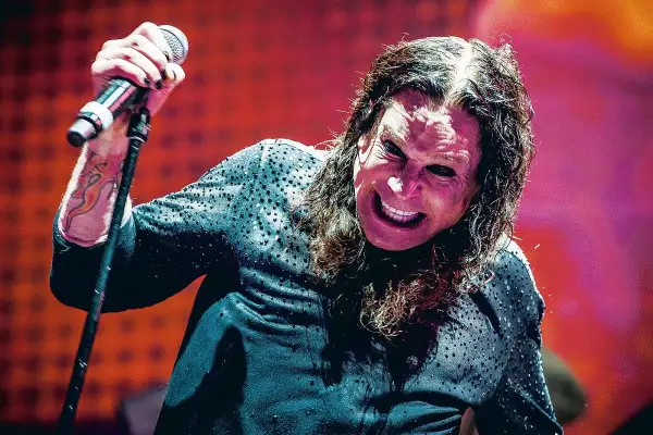Ozzy Osbourne, wokalista Black Sabbath, z mikrofonem w dłoni, z charakterystycznym wyrazem twarzy na koncercie.