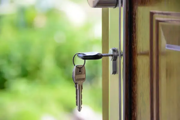 Llaves colgando de una puerta abierta, simbolizando el intercambio de casas entre particulares.