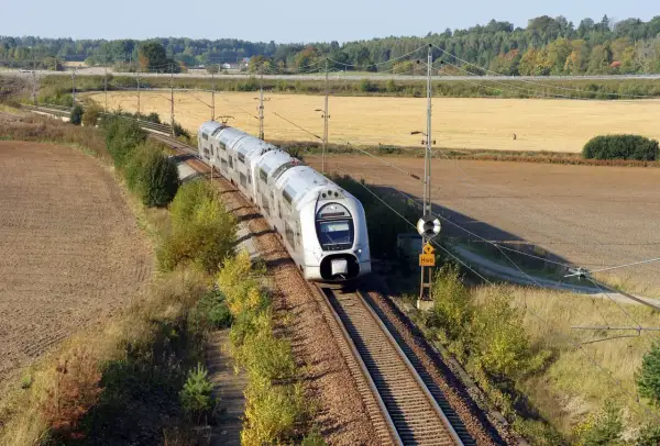 Ett modernt tåg susar fram på spåret genom höstlandskapet. Kanske är det här framtidens tågtekniker utbildning sker, med fokus på effektivitet och miljö.