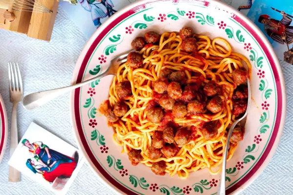 Spaghetti alla chitarra con polpettine in un piatto decorato, pronti per essere gustati.