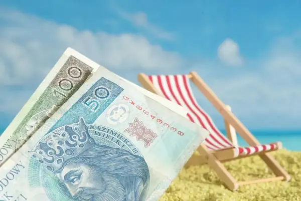 Pieniądze na plaży, leżak i błękitne niebo. Czy niewypłacanie świadczenia urlopowego co to znaczy?