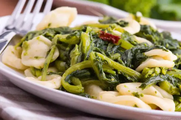 Piatto di orecchiette cime di rapa, un classico della cucina pugliese, con verdure verdi e un tocco di peperoncino.