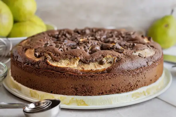 Torta pere e cioccolato, soffice e golosa, con tante gocce di cioccolato e fette di pera che spuntano dalla superficie.
