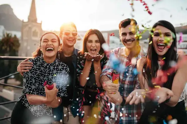 Grupa przyjaciół świętuje, wystrzeliwując konfetti. Idealne życzenia urodzinowe dla 55 latka śmieszne, pełne radości i zabawy!