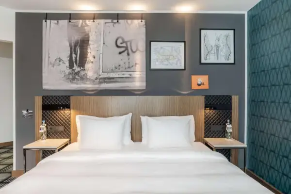 Łóżko w nowoczesnym pokoju hotelowym z białymi pościelami i ozdobami na ścianie.