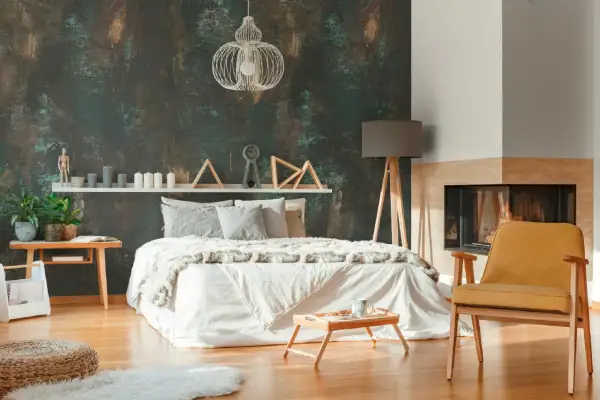 Camera da letto con un letto bianco, camino e una poltrona gialla, il tutto incorniciato da una suggestiva carta da parati effetto corten.