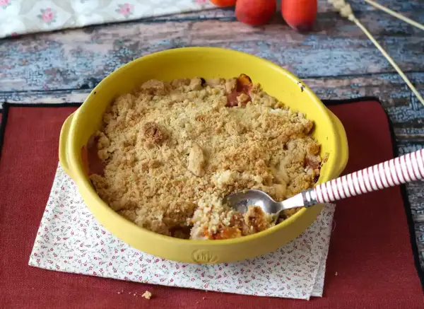 Ein goldbrauner Aprikosen Crumble in einer gelben Auflaufform, bereit zum Genießen.