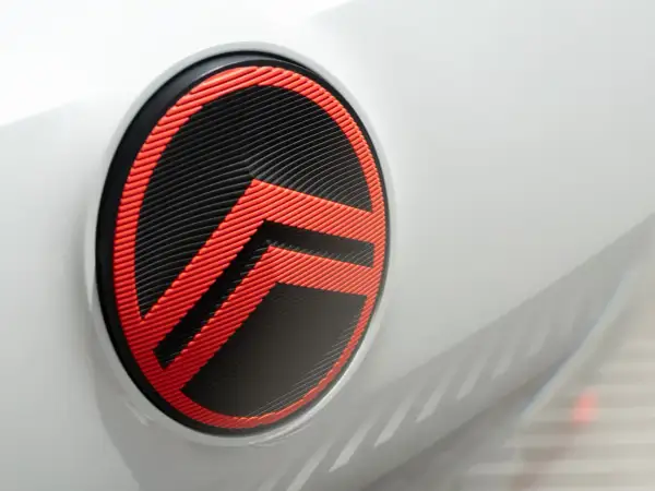 Nowe logo Citroëna w kolorze czarno-czerwonym, z charakterystycznymi jodełkami, zdobi białą karoserię samochodu.