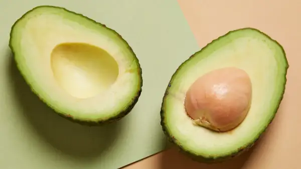 Deux moitiés d'avocat, l'une sans noyau, l'autre avec son noyau. Un aliment sain, mais attention à la prise de poids si consommé en excès.
