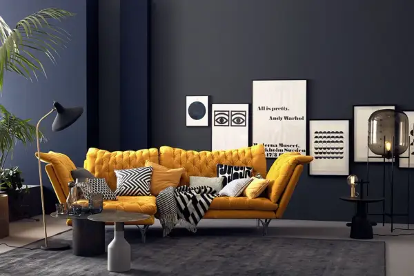 Ein senfgelbes Sofa kombiniert mit grafischen Kissen und einer dunklen Wand schafft einen modernen Look.