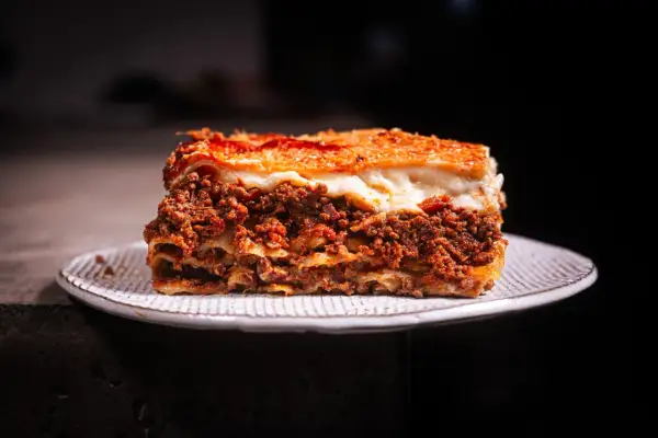 Ein Stück Lasagne mit Hackfleisch und Käse auf einem Teller. Perfekt, wenn man sich fragt, wie lange Lasagne im Ofen braucht.
