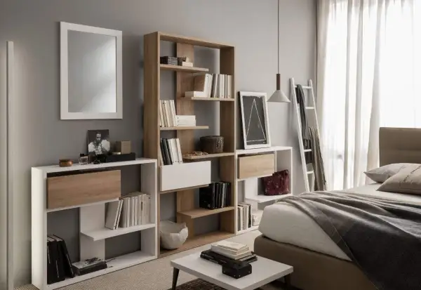 Moderna camera da letto con specchio, letto, e diverse piccole librerie piene di libri e oggetti decorativi.