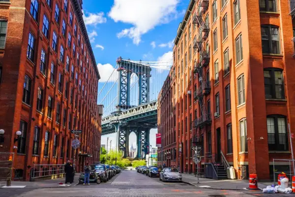 Ulica w dzielnicy DUMBO, Queens, Nowy Jork, z widokiem na most Manhattan Bridge między ceglanymi budynkami.