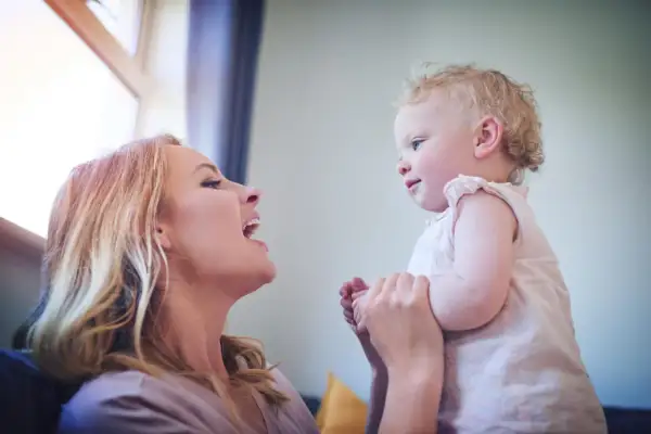 Radosna mama patrzy na swoje dziecko, które właśnie zaczyna mówić "mama".