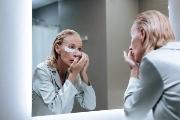Femme appliquant des patchs sous les yeux, découvrant les matrixyl bienfaits pour une peau rajeunie.