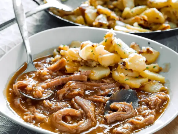 Herzhaftes Kutteln Rezept mit goldbraunen Bratkartoffeln, garniert mit Petersilie. Ein Löffel voller Genuss.