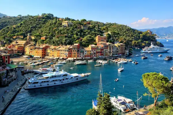 Portofino: cosa vedere? Un incantevole borgo ligure con case colorate, un porto pieno di yacht e una collina verdeggiante.