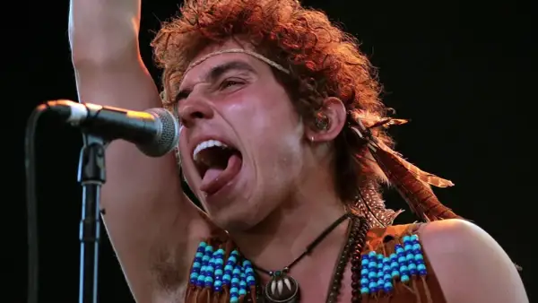 Josh Kiszka z Greta Van Fleet, jeden z członków zespołu, śpiewa z pasją do mikrofonu, ozdobiony piórami i koralikami.