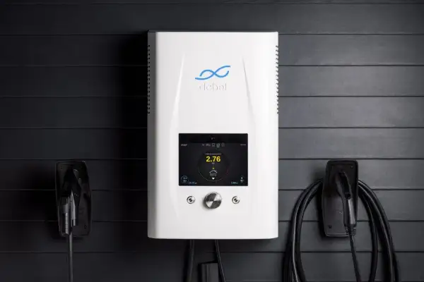 Biała ładowarka do samochodów elektrycznych z ekranem dotykowym, obok niej wiszą kable. To zaawansowany silnik inwerterowy.