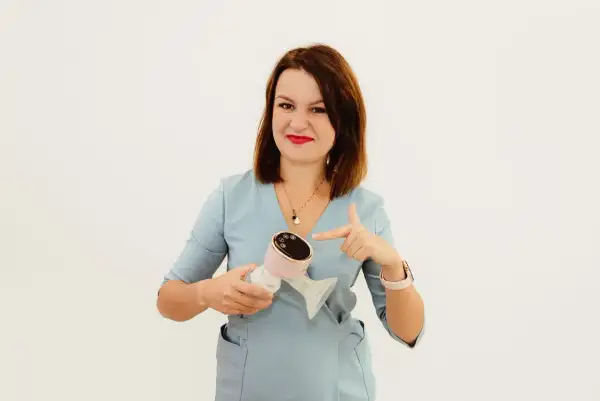 Kobieta w niebieskim fartuchu wskazuje na różowy laktator. To idealne rozwiązanie dla mam, które cenią sobie wygodę i nowoczesność, jak w przypadku Milanella Complex.