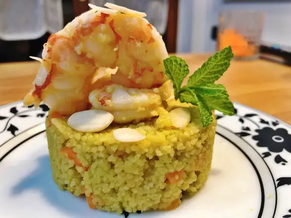 Un elegante cous cous gourmet con gamberi, mandorle e menta, un piatto raffinato.