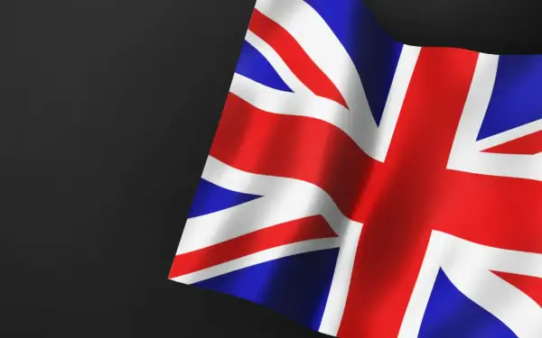 Flaga Wielkiej Brytanii, symbol nadziei na pozwolenie na pracę w UK dla Polaków. Czerwono-biało-niebieskie pasy falują na ciemnym tle.