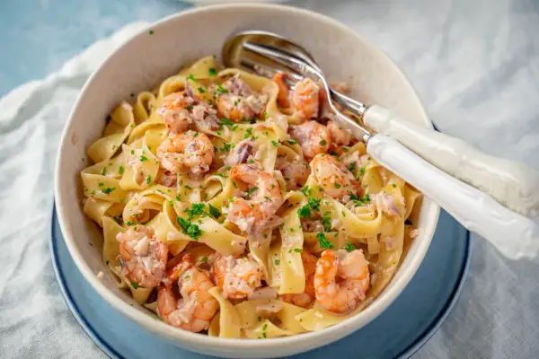 Breite Bandnudeln mit saftigen Garnelen in cremiger Sauce, garniert mit frischer Petersilie. Ein köstliches Gericht mit Nudeln mit Garnelen.