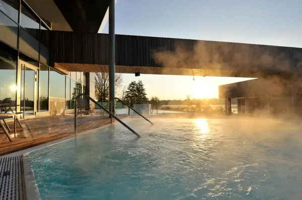 Dampf steigt aus einem Pool auf, während die Sonne über Brandenburg aufgeht. Ein perfekter Ort für einen erholsamen Urlaub.