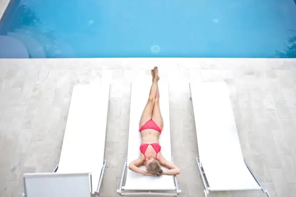 Kobieta w bikini odpoczywa przy basenie. Cieszy się słońcem po zabiegu depilacja bikini płytkie.