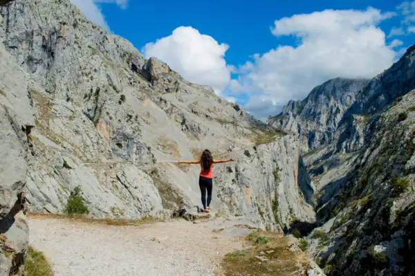 Mujer con brazos extendidos en un desfiladero rocoso, disfrutando de la vista. ¡Una aventura de Cantabria en 4 días!