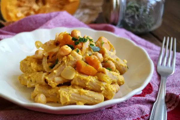 Piatto di pasta con la zucca, ceci e cipolla, guarnito con prezzemolo fresco. Un comfort food autunnale.