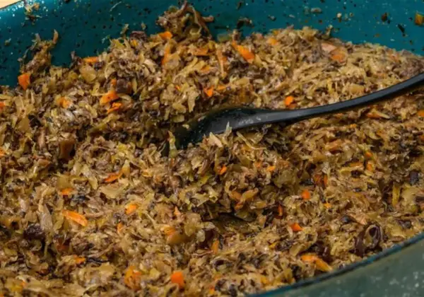 Pyszne, domowe pierogi z kapustą i grzybami, gotowe do podania. Czarna łyżka miesza aromatyczny farsz.