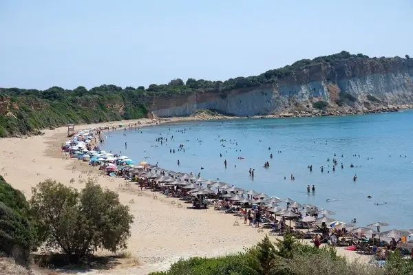 Piękna plaża na wyspie Kos, pełna ludzi kąpiących się i opalających. Uważaj na słońce i tłumy, by w pełni cieszyć się wakacjami.