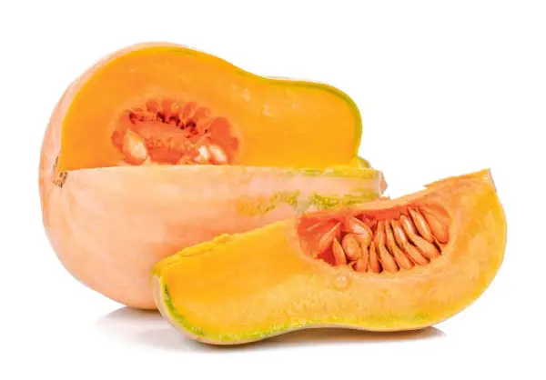 Pomarańczowa dynia, przekrojona na pół, z widocznymi nasionami. Obok leży plasterek tej samej odmiany dyni.