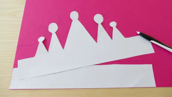 Sagoma di una corona da colorare su carta fucsia, pronta per essere ritagliata e decorata.