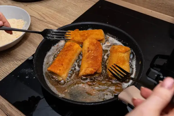 Chrupiące krokiety z pieczarkami smażą się na złoto na patelni.