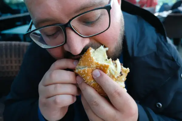 Mężczyzna w okularach je dużego burgera.