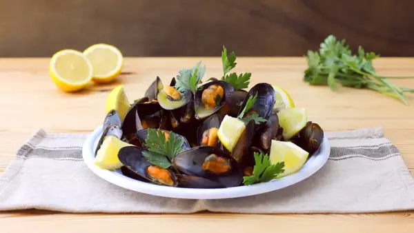Un piatto invitante di impepata di cozze, guarnito con spicchi di limone fresco e prezzemolo, pronto per essere gustato.