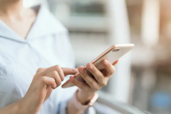 Dłoń trzyma telefon, szukając instrukcji, jak wyłączyć tryb awaryjny w telefonie.
