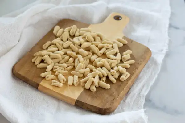 Un mucchio di cavatelli pugliesi freschi su un tagliere di legno, pronti per essere cucinati.