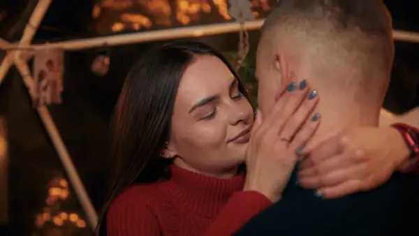Bliska, intymna chwila pary. Ona zamyka oczy, dotykając jego policzka. Sekret jak rozkochać w sobie faceta na odległość? Bliskość, nawet w oddali.