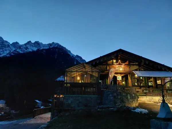 Rifugio alpino illuminato con una stella di Natale, circondato da montagne innevate. I forni di sopra sono spenti, ma l'atmosfera è calda e accogliente.