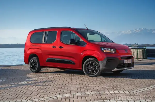 Fiat Qubo rosso fiammante parcheggiato sul lungolago, con montagne innevate sullo sfondo. Le diverse fiat qubo motorizzazioni offrono versatilità.