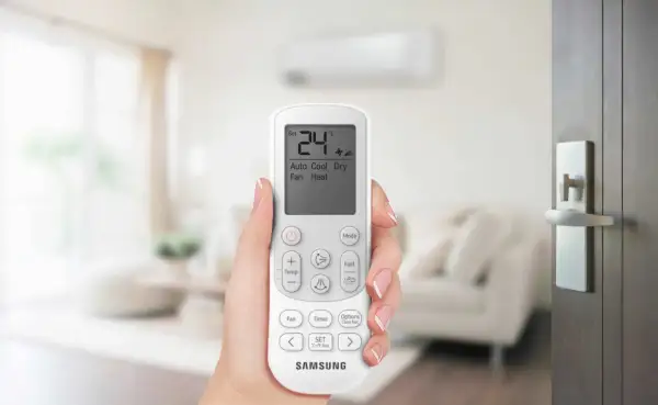 Mano che tiene il telecomando di un condizionatore Samsung. Il display mostra 24°C, Auto, Cool, Dry, Fan, Heat. Il significato di un condizionatore potente è il comfort.