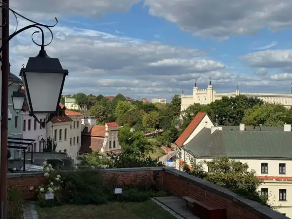 Widok na Lublin na weekend. Zabytkowe kamienice, zieleń i biały zamek na wzgórzu pod błękitnym niebem.