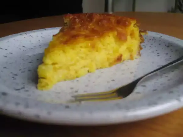 Una rebanada de torta de maiz dorada y esponjosa en un plato, lista para ser disfrutada con un tenedor.