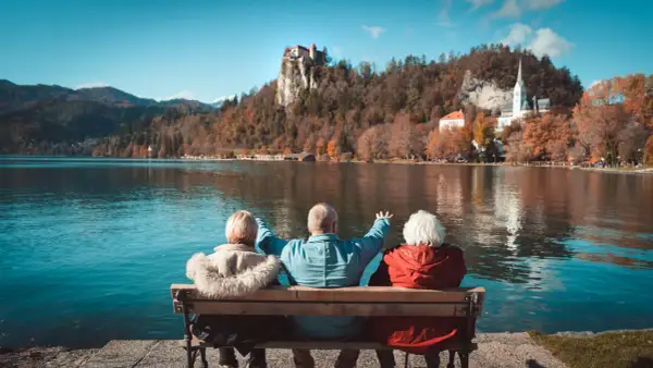 Trzech seniorów cieszy się widokiem zamku na skale i jeziora. Idealne wczasy pod gruszą dla emeryta.