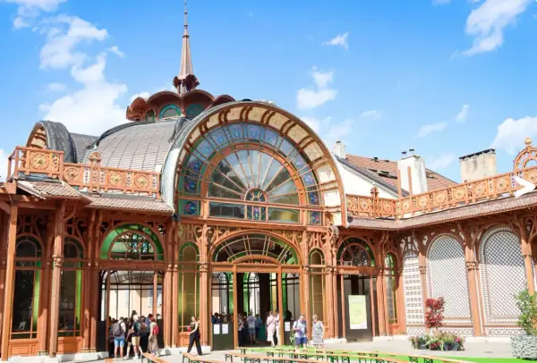 L'architecture Art Nouveau du Palais Lumière à Évian-les-Bains, avec ses vitraux colorés et sa structure en bois, sous un ciel bleu.