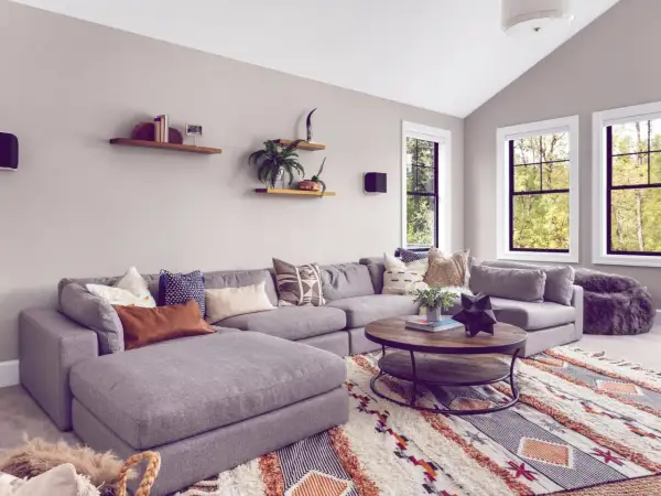 Gemütliches Wohnzimmer mit großem Ecksofa, Kaffeetisch und einem auffälligen Teppich im Boho-Stil, der den aktuellen Teppich Trend widerspiegelt.
